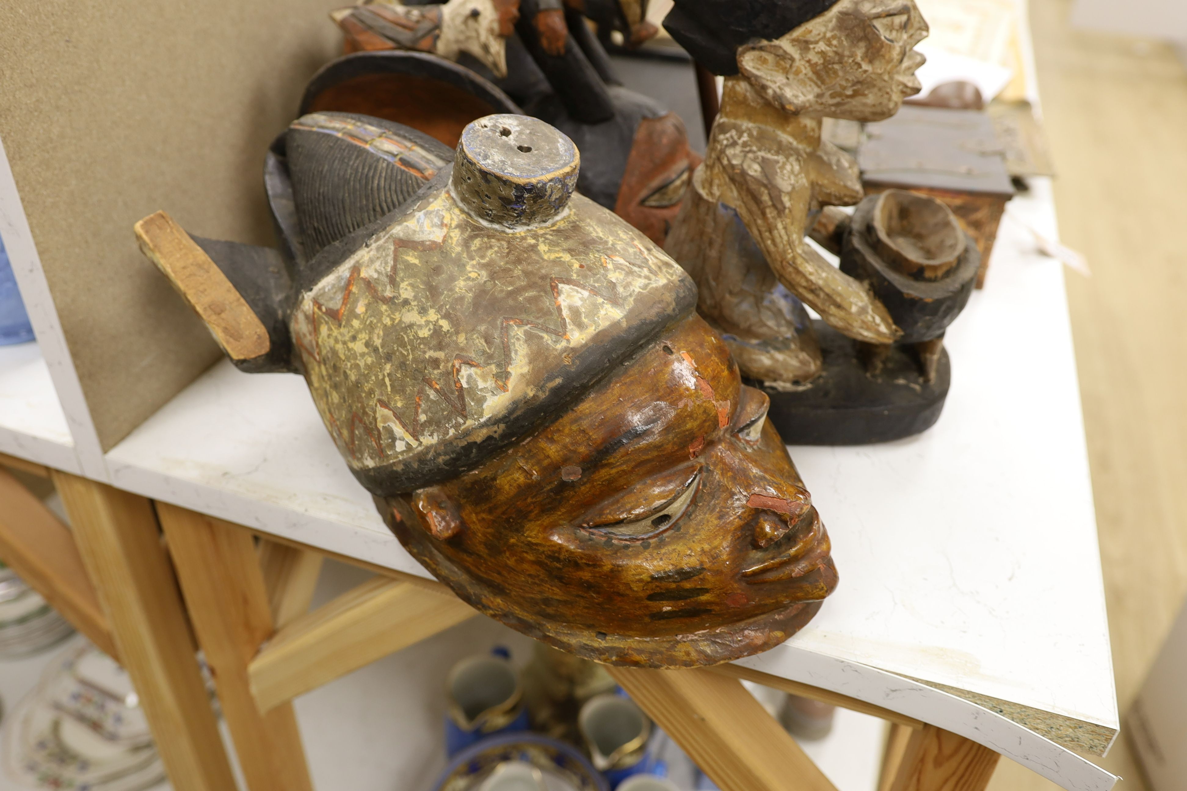 A group of West African tribal artefacts, including a Cross River Egungun mask, 48 x 20cm, a Yoruba Gelede helmet mask, 39 x 38cm and a Yoruba offering figure, 35cm, Provenance- collected by the owner’s uncle before 1960